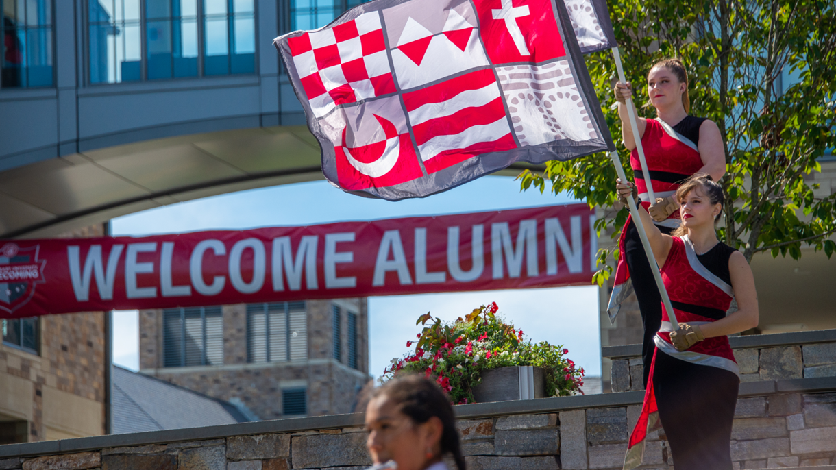 Welcome Alumni sign with flags and girls