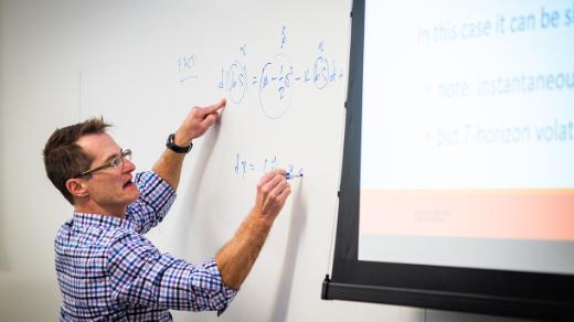 A professor writing on a white board in class
