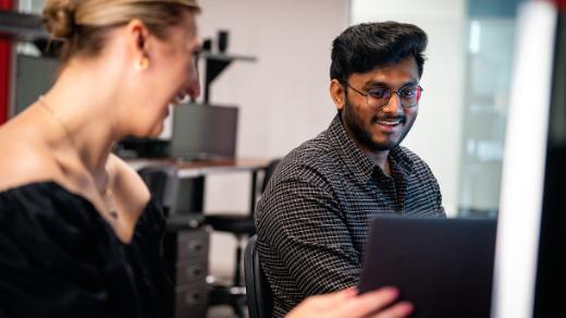 two people in a class looking at computers and smiling