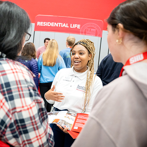 an admissions representative talking with a mom and daughter about residential life options at Sacred Heart University