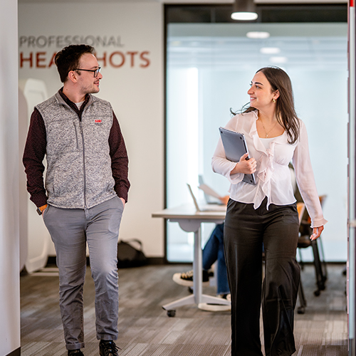 two people walking and talking in an office