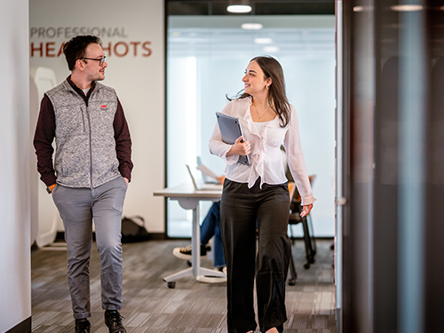 Two professionals walking and talking in an office setting