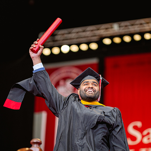 a happy graduate holding their diploma in the air