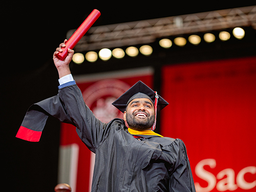 a happy graduate holding their diploma in the air