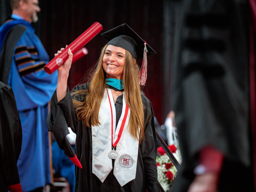 Student holding up diploma after graduating