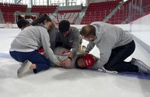 Athletic trainers assisting hurt hockey player on the ice