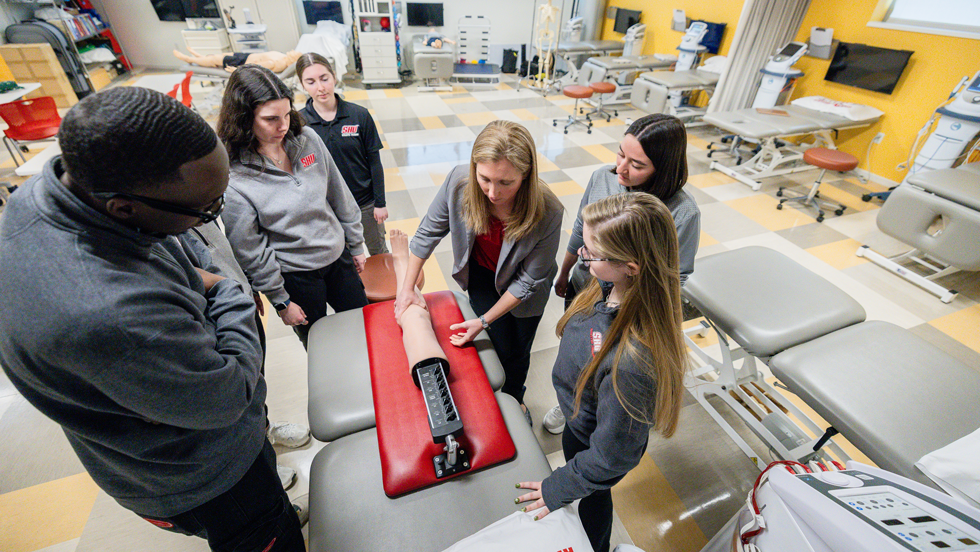 Faculty and students working with a prosthetic limb in the AT lab