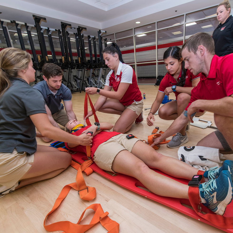Athletic training students practicing helping an injured person