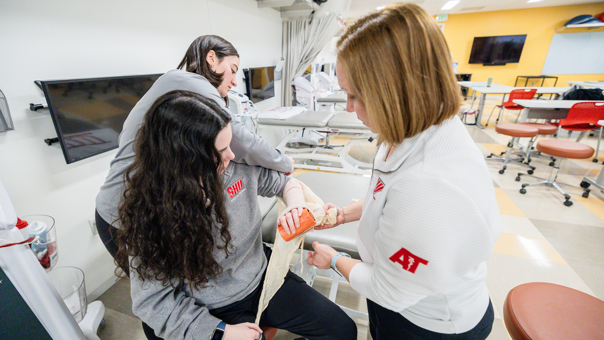 Athletic training students and professor learning how to wrap an injury