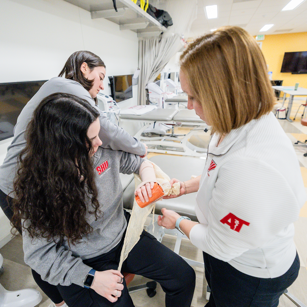 Athletic training students and professor learning how to wrap an injury