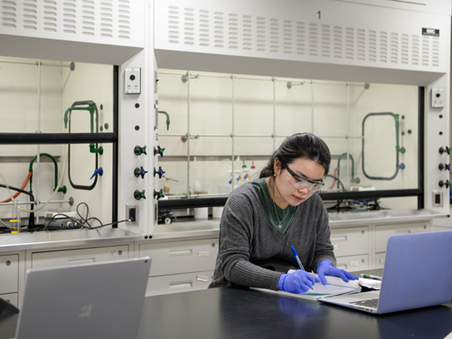 Student writing down information in lab