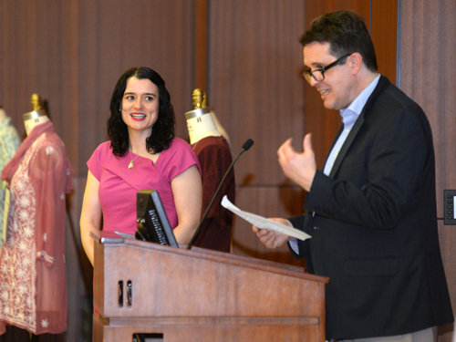 Professor speaking at podium with woman looking at him