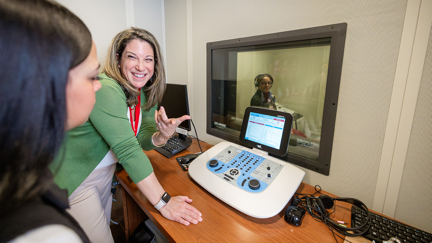 Professor working with a student in an audiology clinic