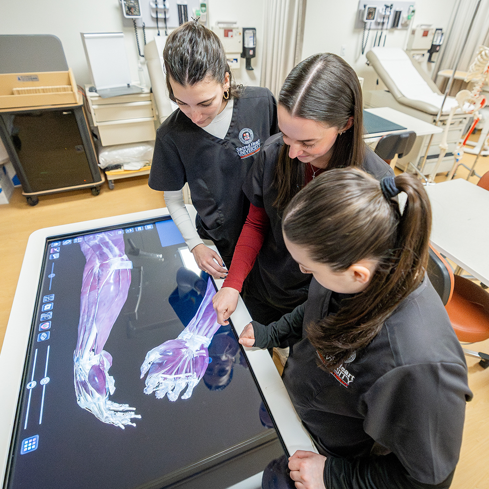 OT students using an anatomage table to study anatomy