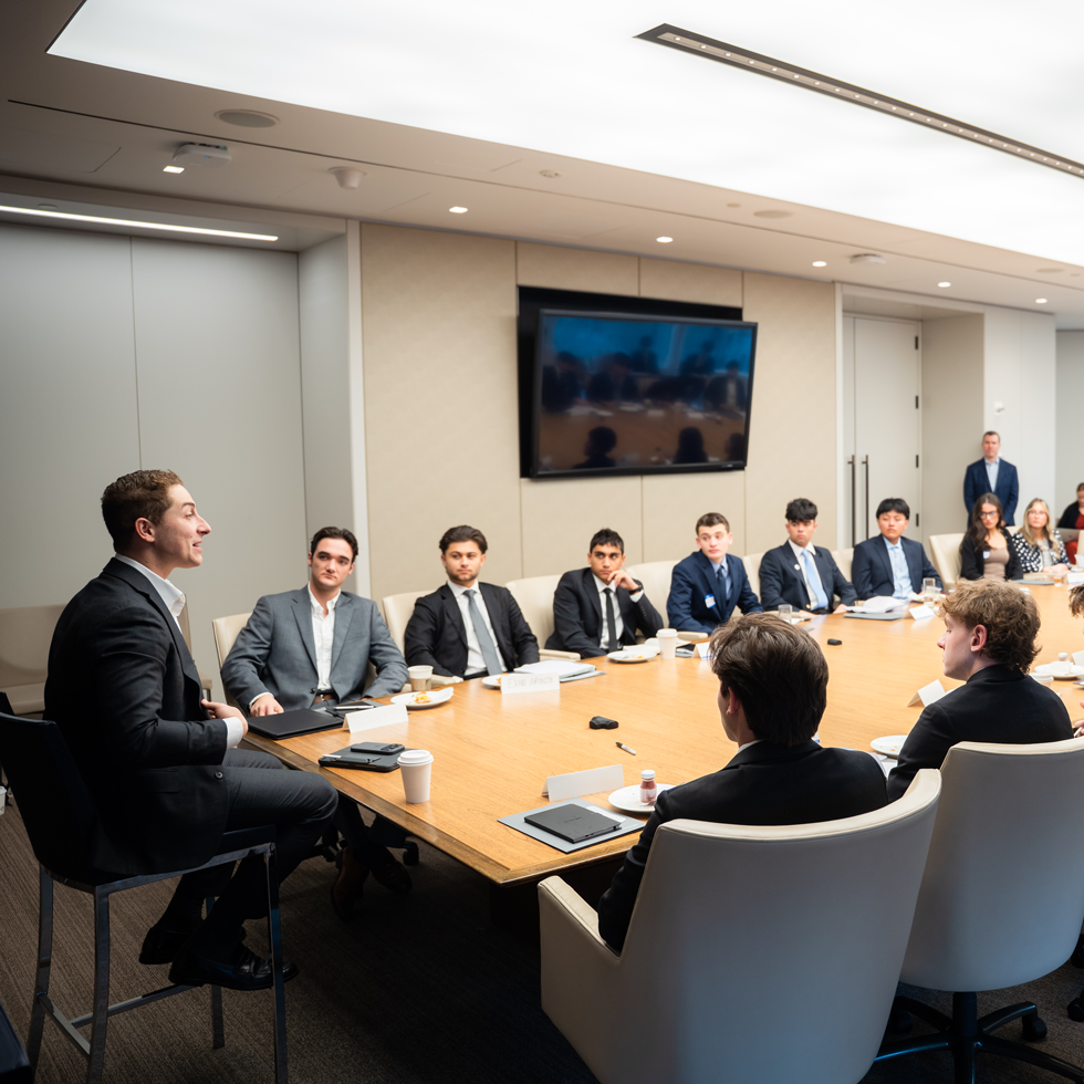 Business students visiting a corporate office and listening to professional at conference table
