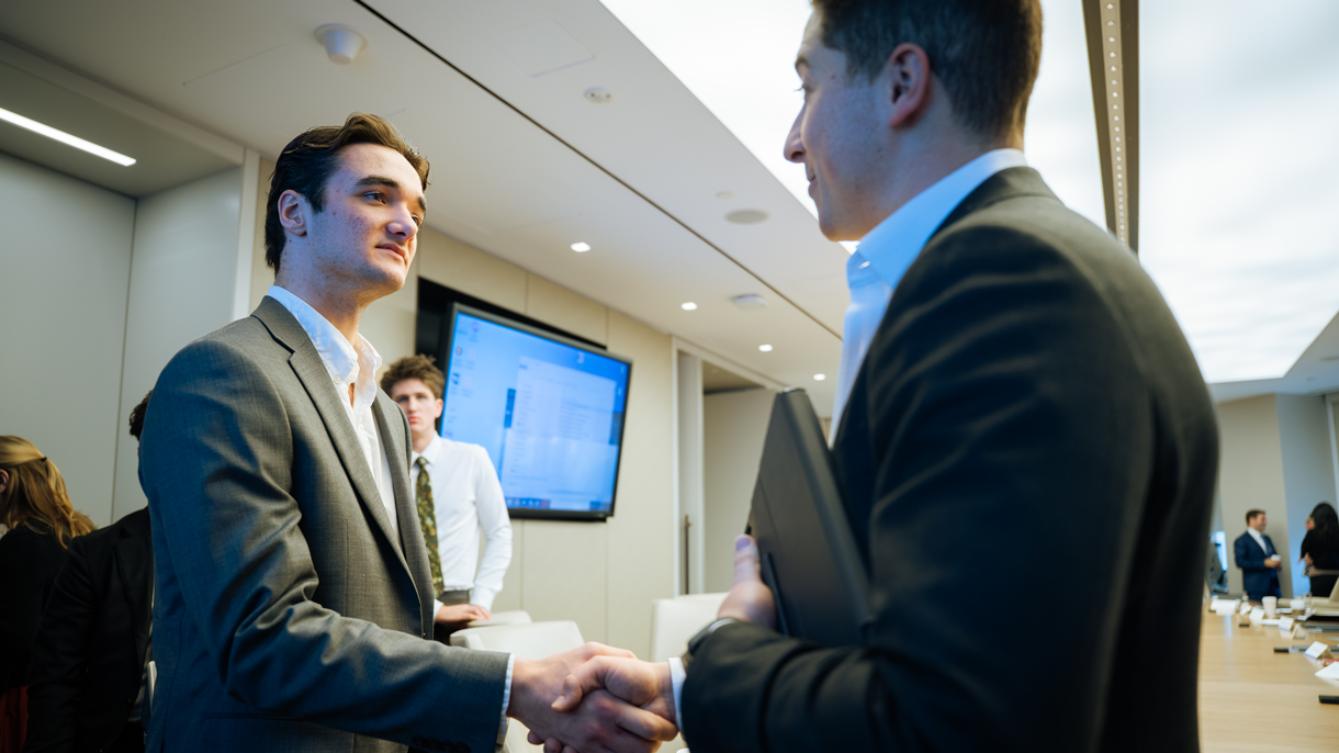 Business student shaking professionals hand