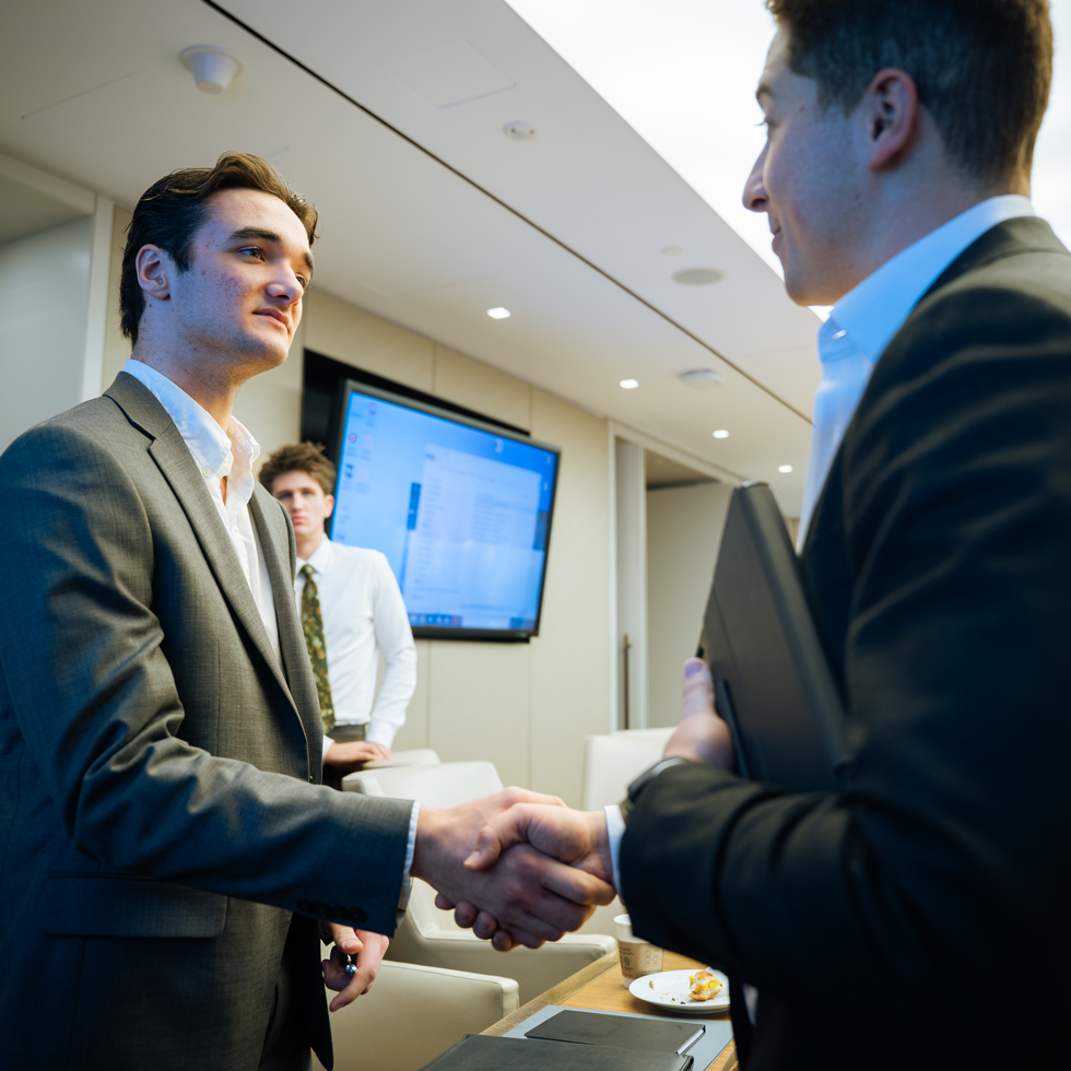 Business student shaking professionals hand