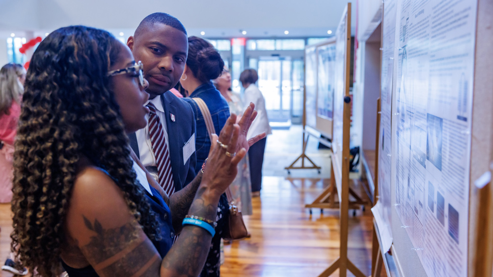 Student describing research poster to faculty member