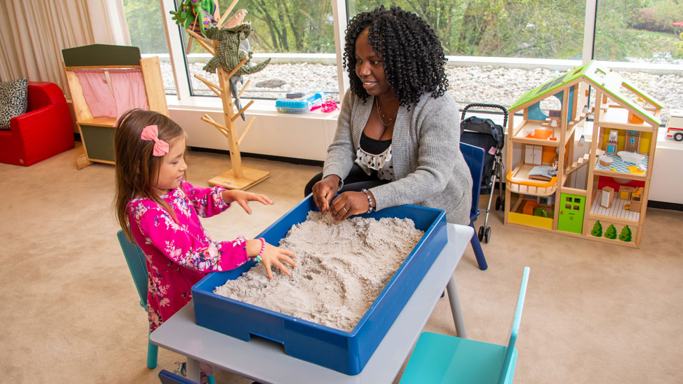 Student playing in a sensory sandbox with child