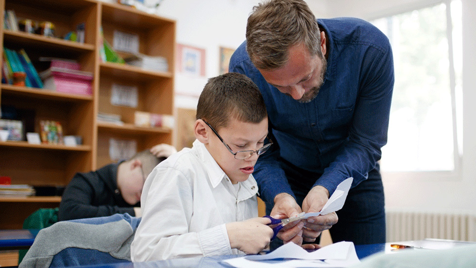 Teacher helping student use scissors