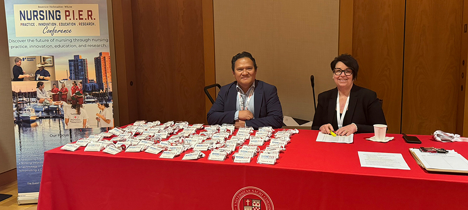 two people sitting at a conference registration table