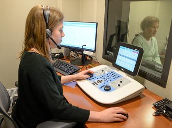 An audiologist testing the hearing of a patient with equipment