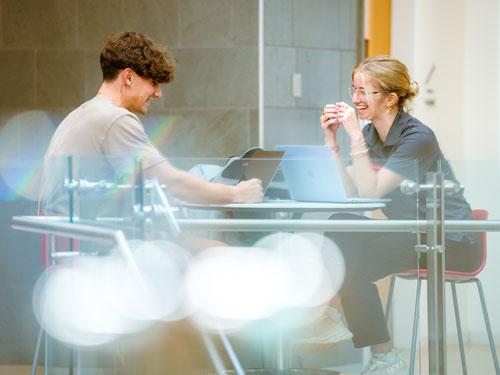 Two students sitting at table and laughing