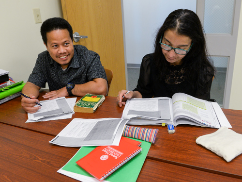 Two people looking at books in a classroom