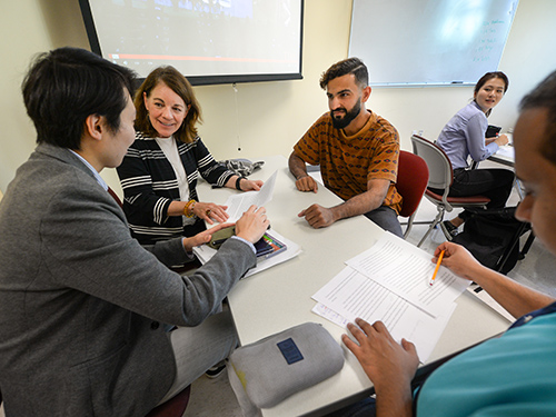 An instructor working with students at a table during class