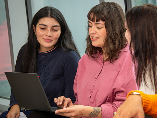 three people looking at a laptop computer