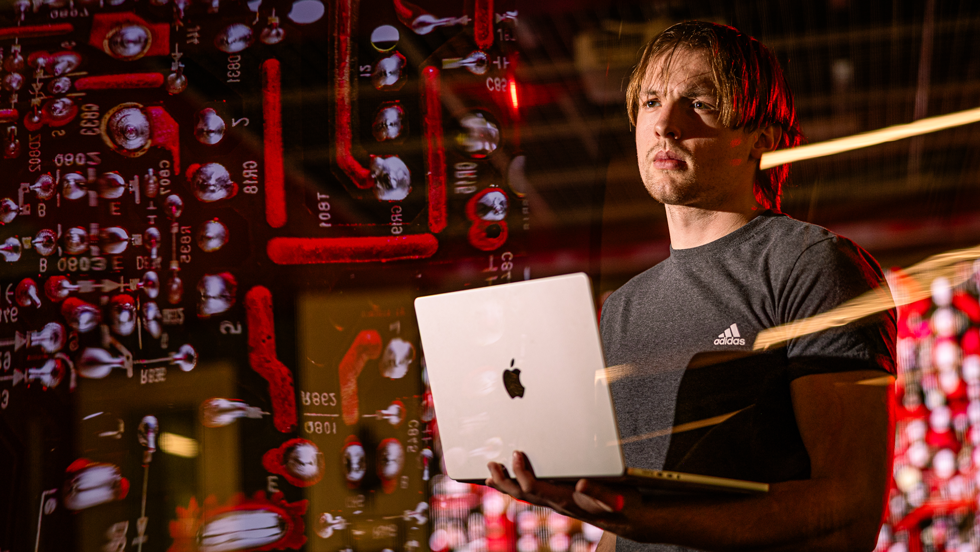 Student holding laptop with code superimposed over image