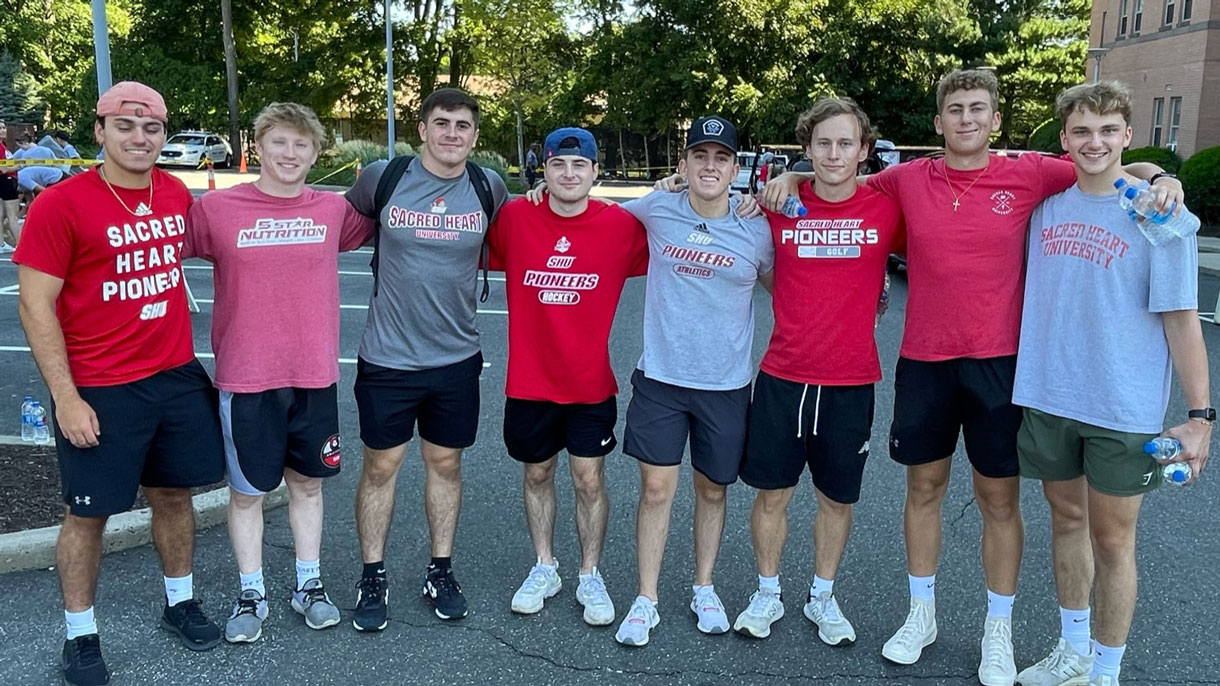 Members of Sigma Chi wearing Sacred Heart University gear and posing for photo