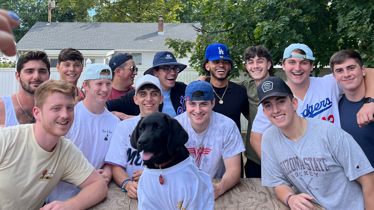 Members of Sigma Chi posing with a dog in a t-shirt