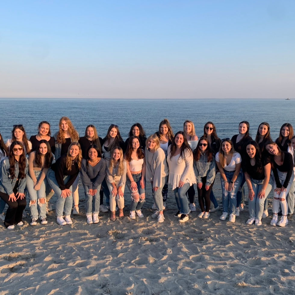 Members of Tri Delta on the beach during sunset posing for photo