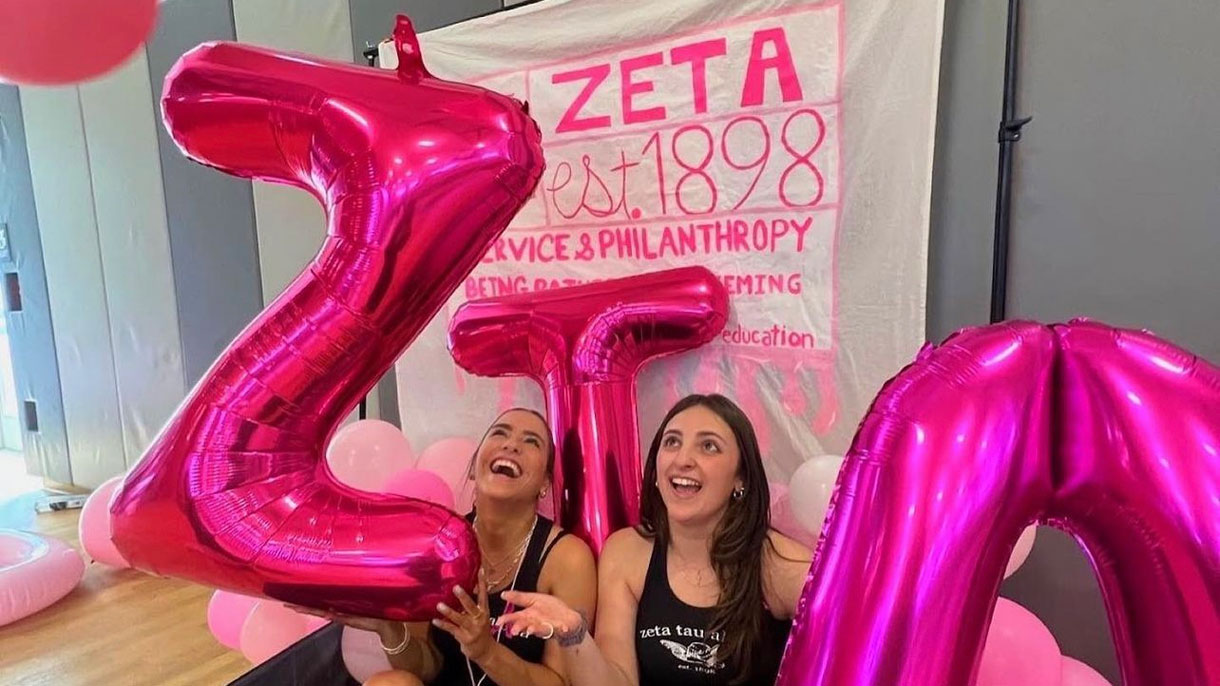 Members of Zeta Tau Alpha at their philanthropy event. Large pink balloons in the shape of their letters 