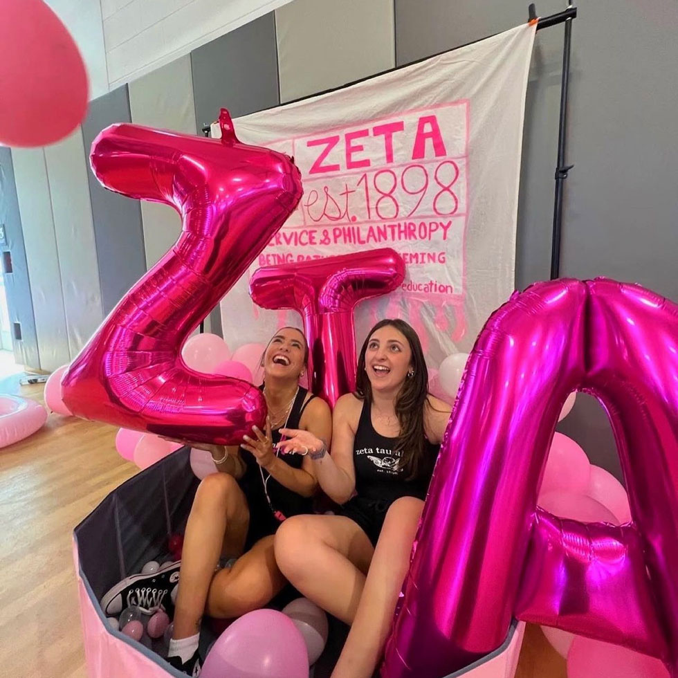 Members of Zeta Tau Alpha at their philanthropy event. Large pink balloons in the shape of their letters 