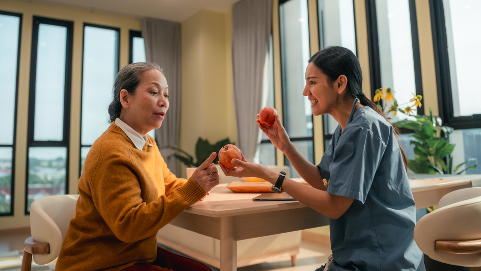 Health care worker showing an apple to a woman