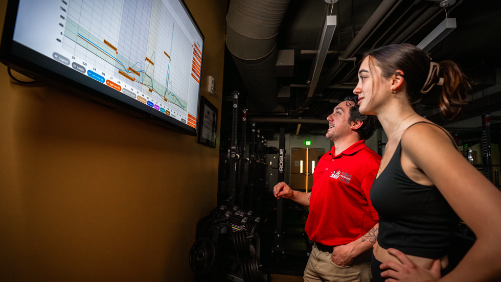 Two people looking at a data graph on a TV screen