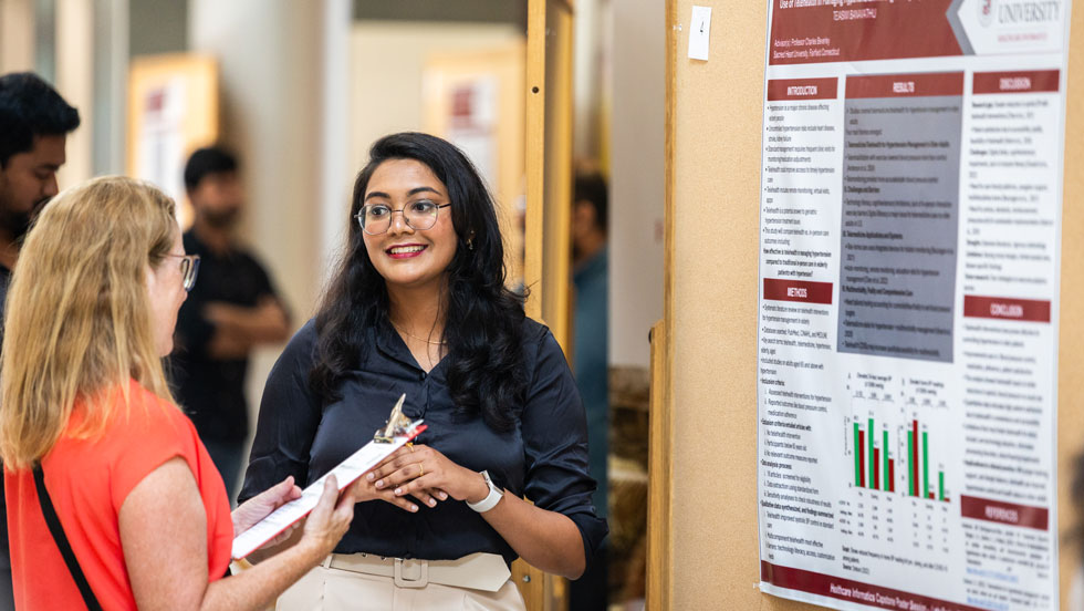Student explaining capstone poster to professor
