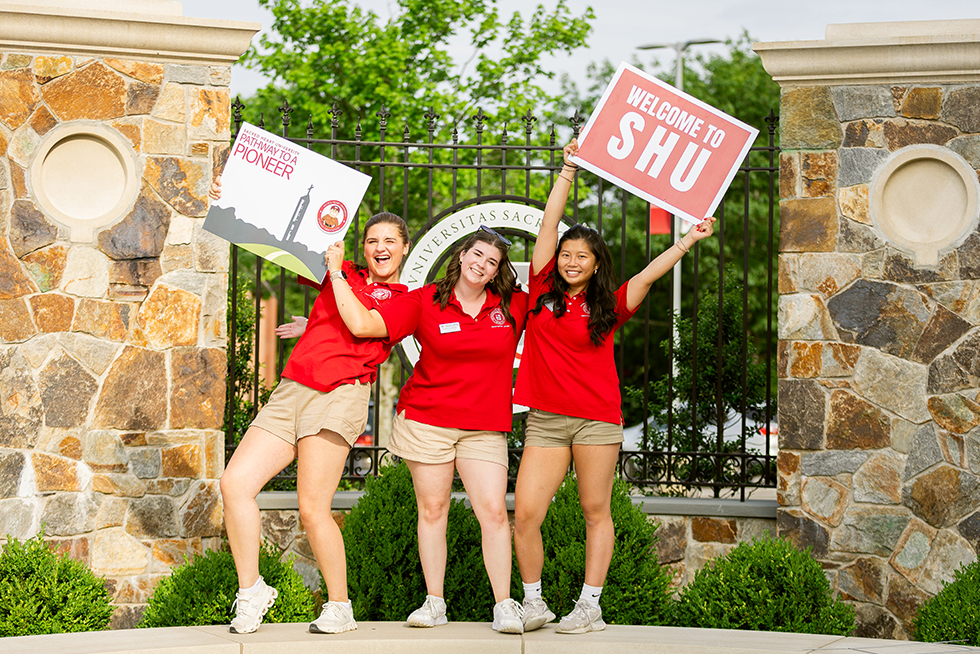 three cheering college students holding up signs