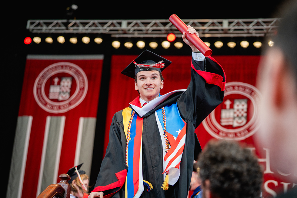 A graduate waving their diploma in the air