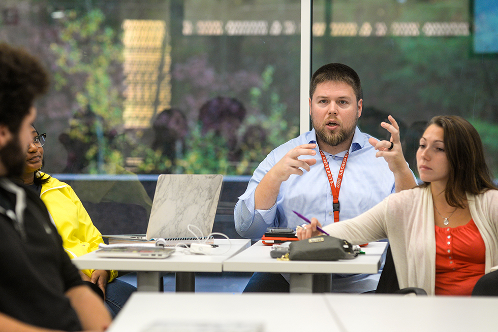a professor gesturing in a classroom with other students