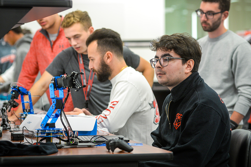 a college student in class looking at his robot creation