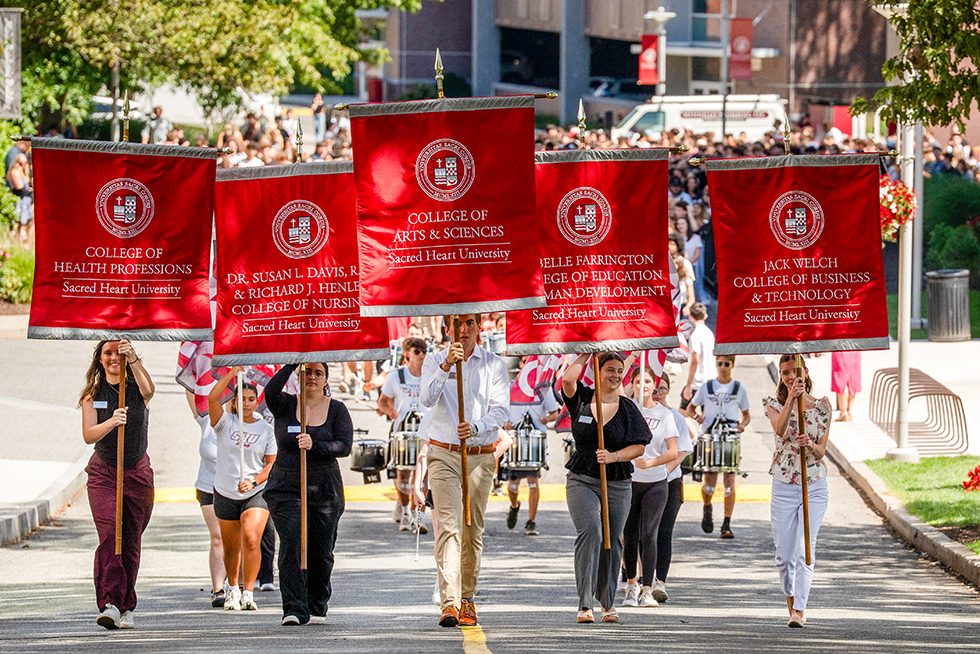 a walking parade led by five college students holding red banners