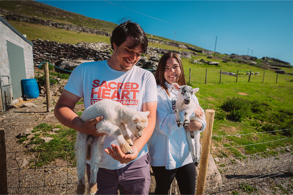 two college students holding lambs in the Dingle Ireland landscape