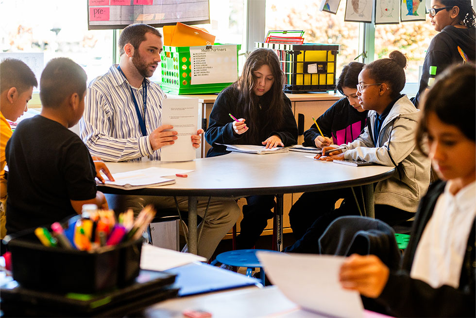 A student teacher working with children in an elementary school classroom