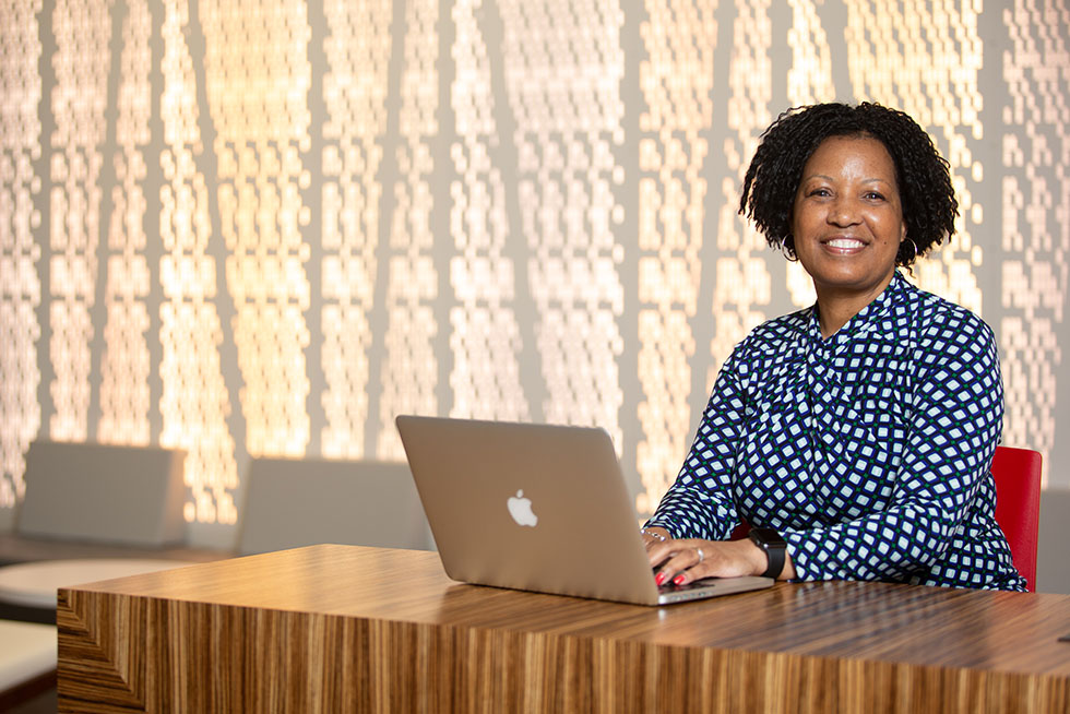 a smiling person working on a laptop computer