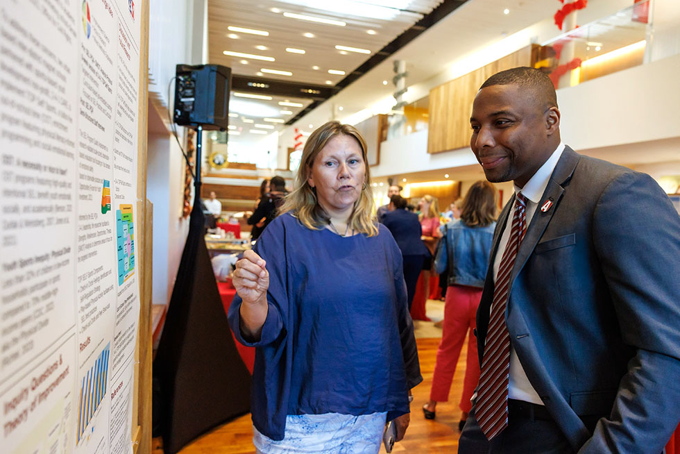 Two people discussing graduate research at a poster presentation