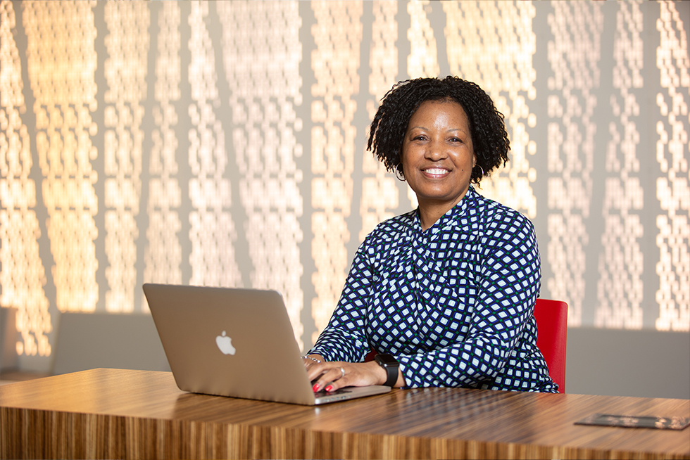 a smiling graduate student working on their laptop
