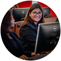Two college students looking at a computer screen in class